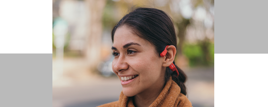 Up-close image of Latina woman smiling and wearing Shokz OpenRun wireless headphones